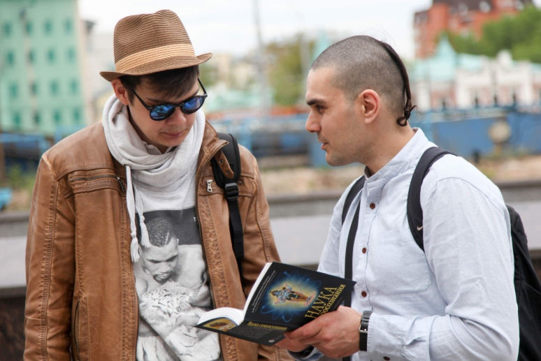 Санкиртанщик предлагает книгу людям на улице